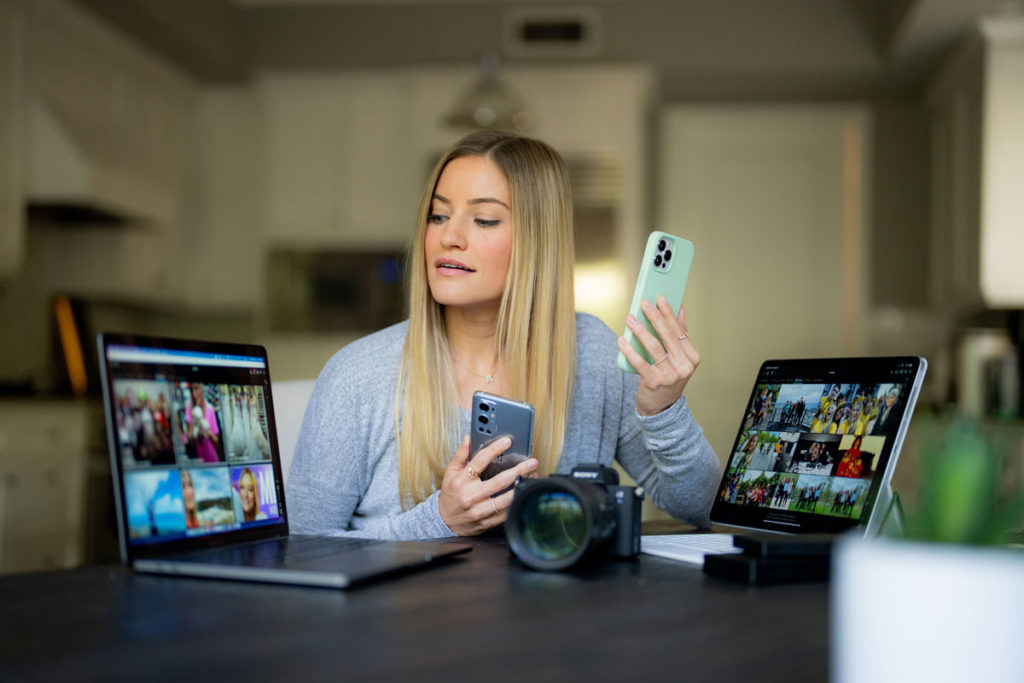 iJustine looks at the Mylio photo app on her phone and laptop computers.