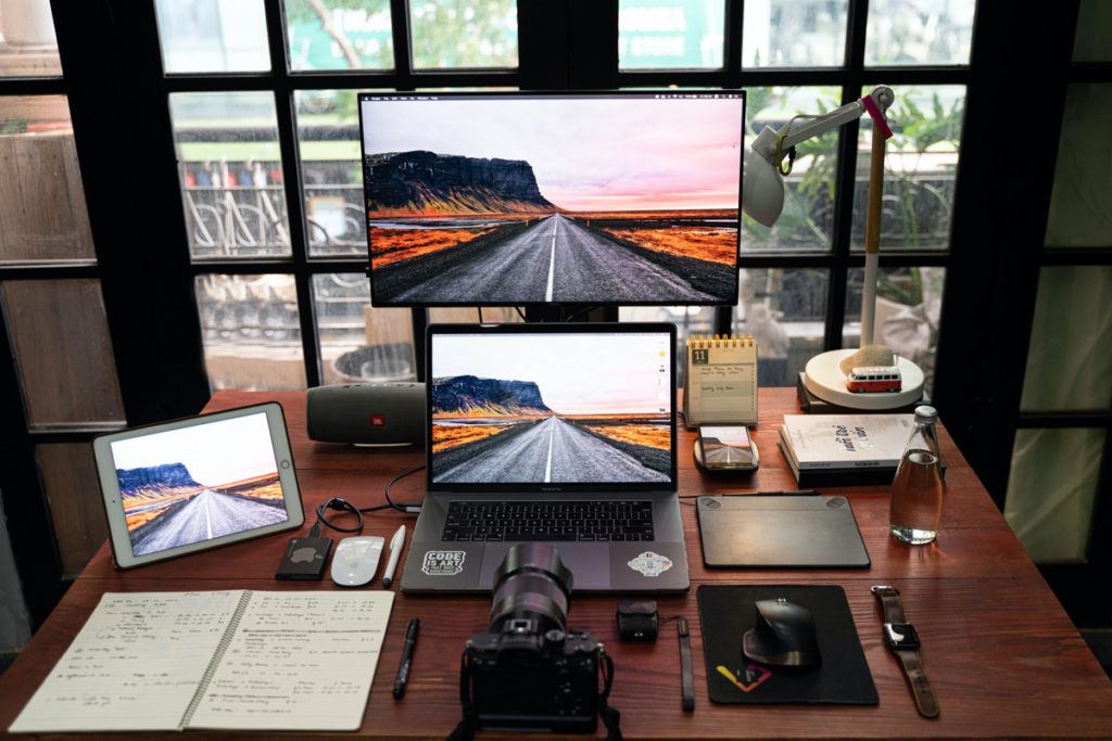 Desk with a computer, tablet, camera, and notebook