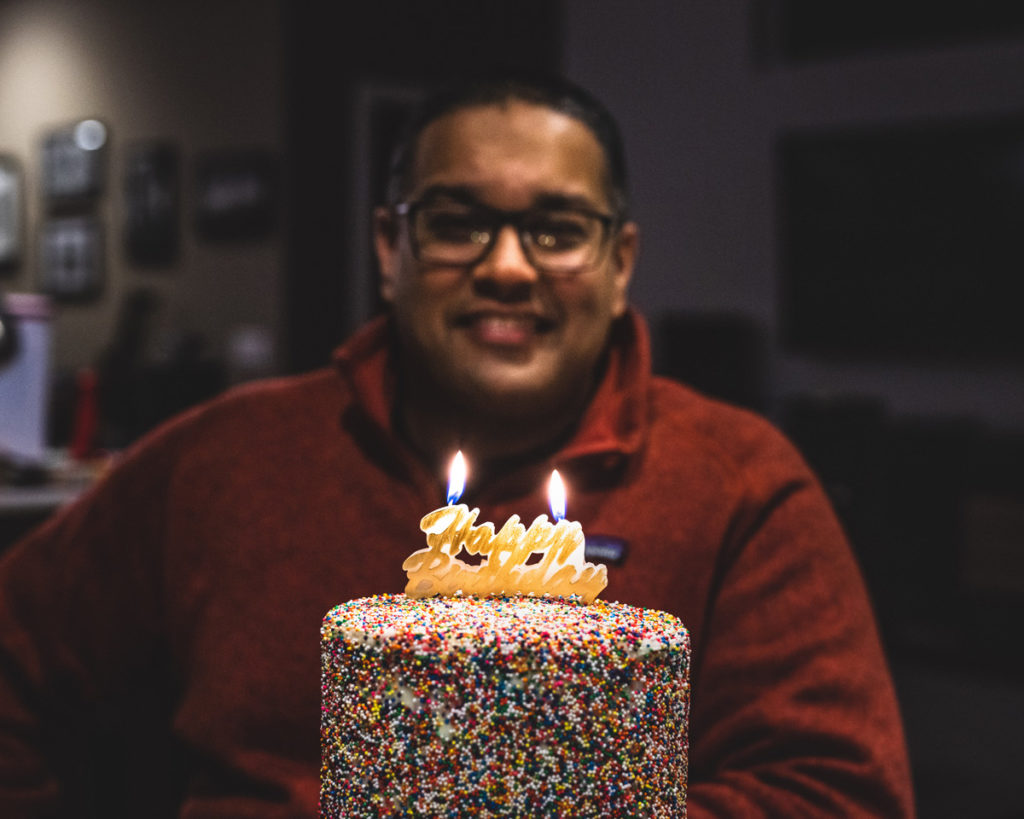 Smiling man in front of birthday cake with candles lit
